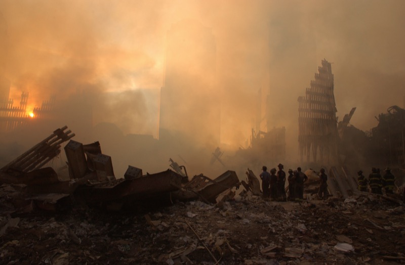 Firefighters stand amid the ruins of the World Trade Center, shrouded in smoke and toxic dust, September 13, 2001